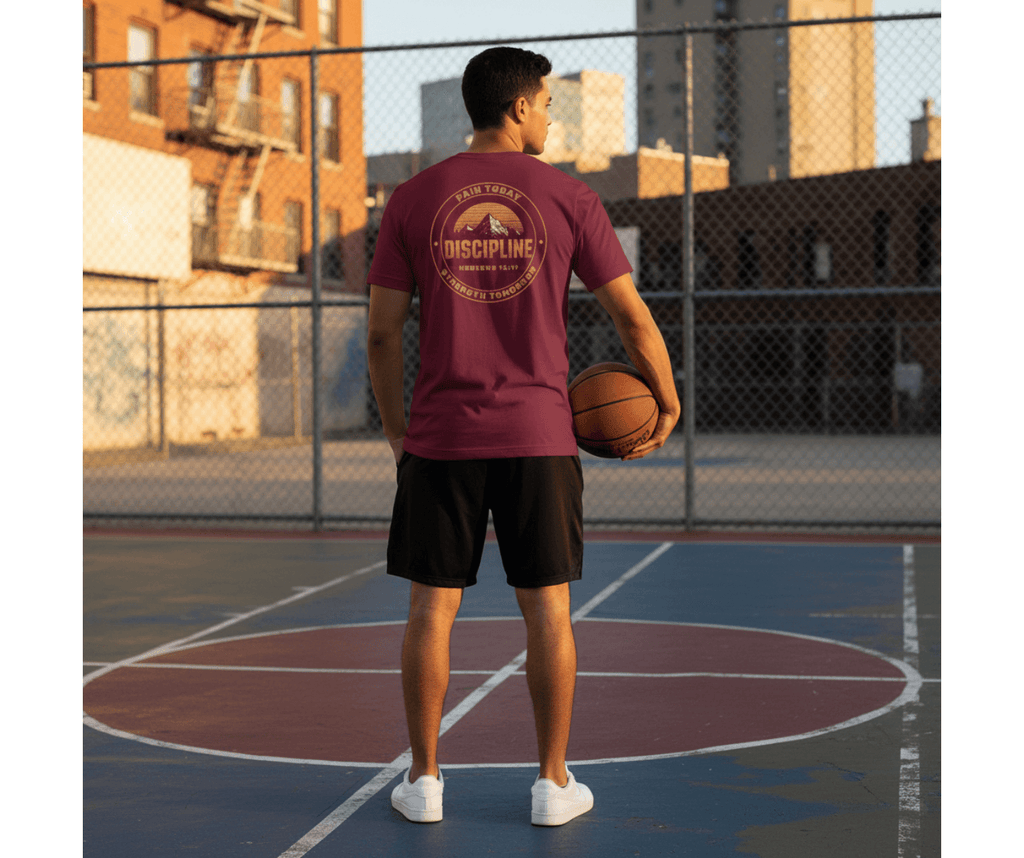 Person holding a basketball on an outdoor court with a maroon t-shirt and black shorts.