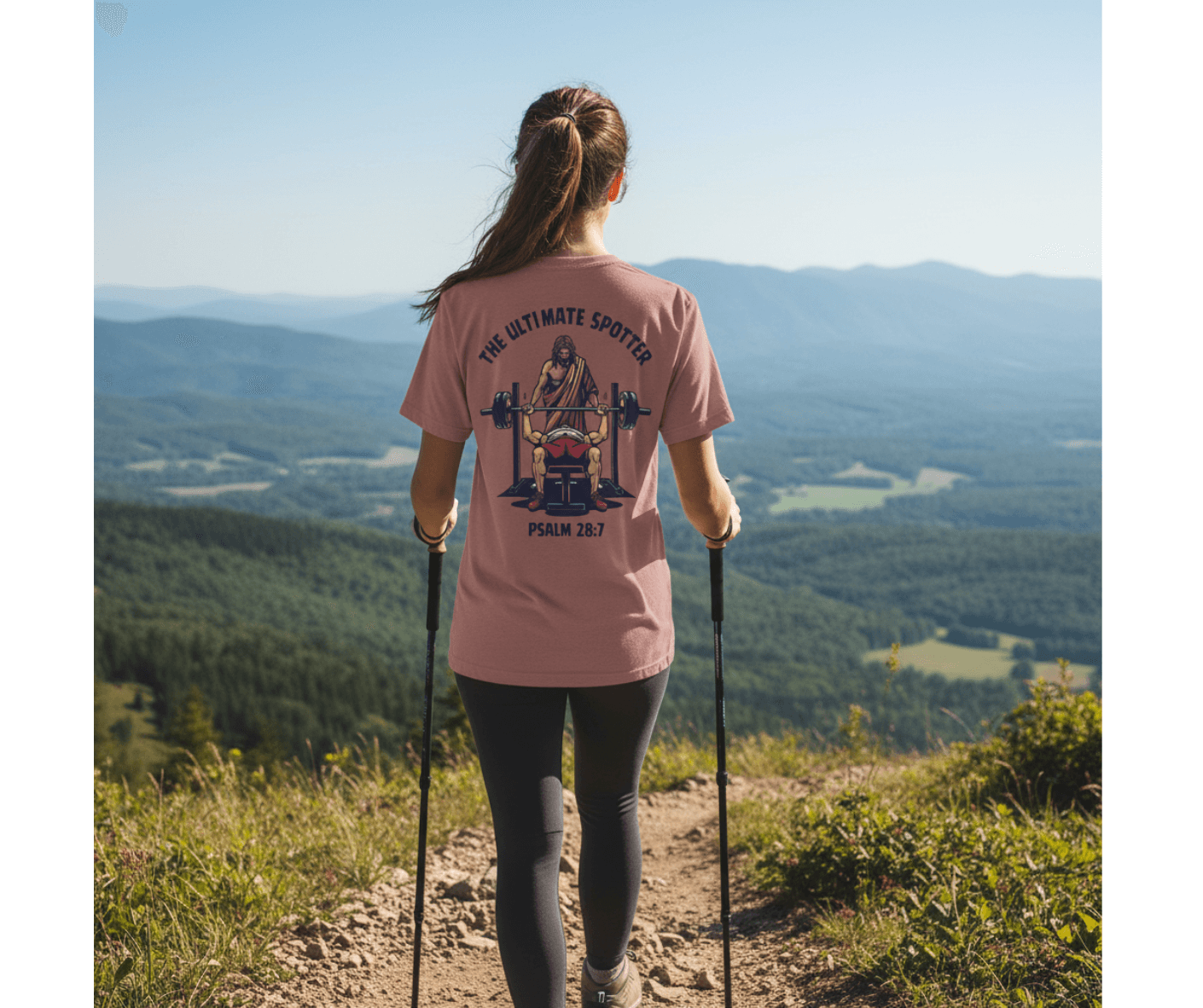 Person hiking with a scenic view, wearing a pink t-shirt with a graphic design.