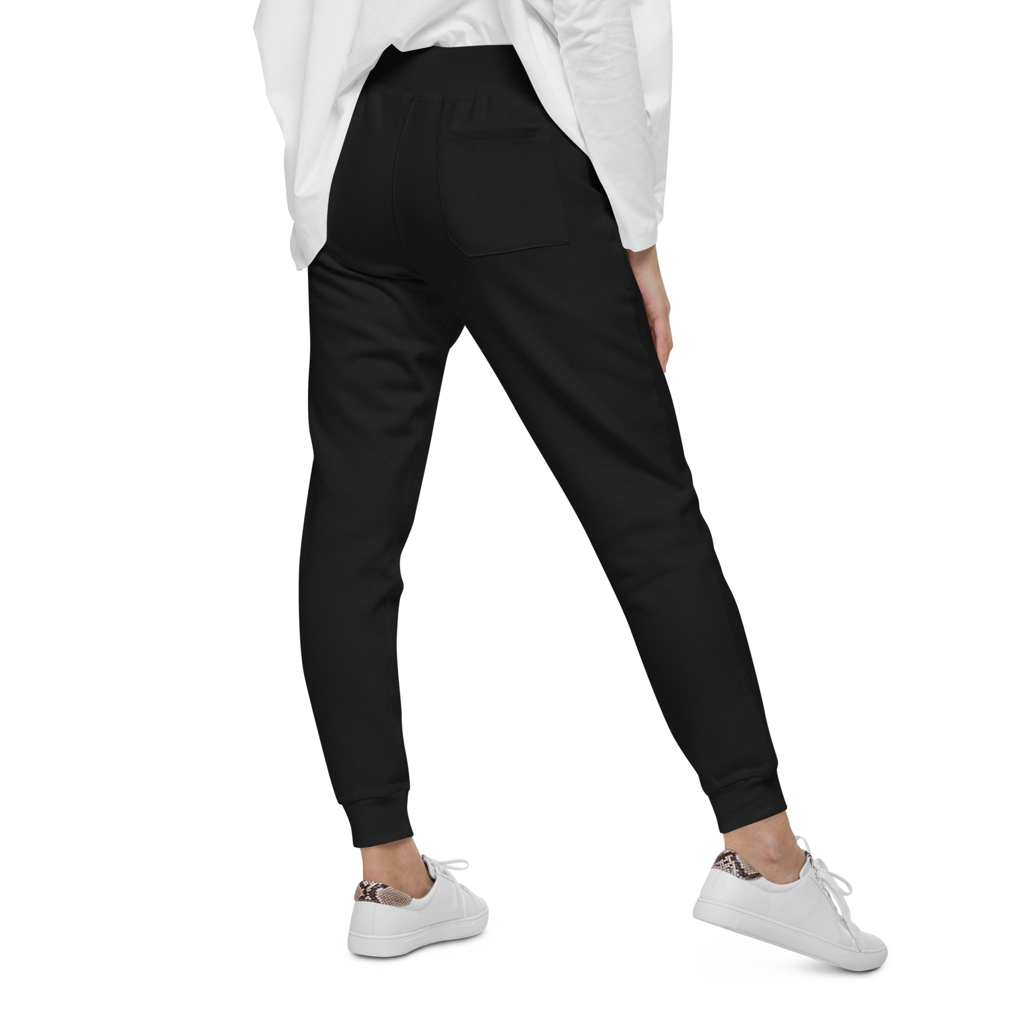 Person wearing black jogger pants and white sneakers on a white background