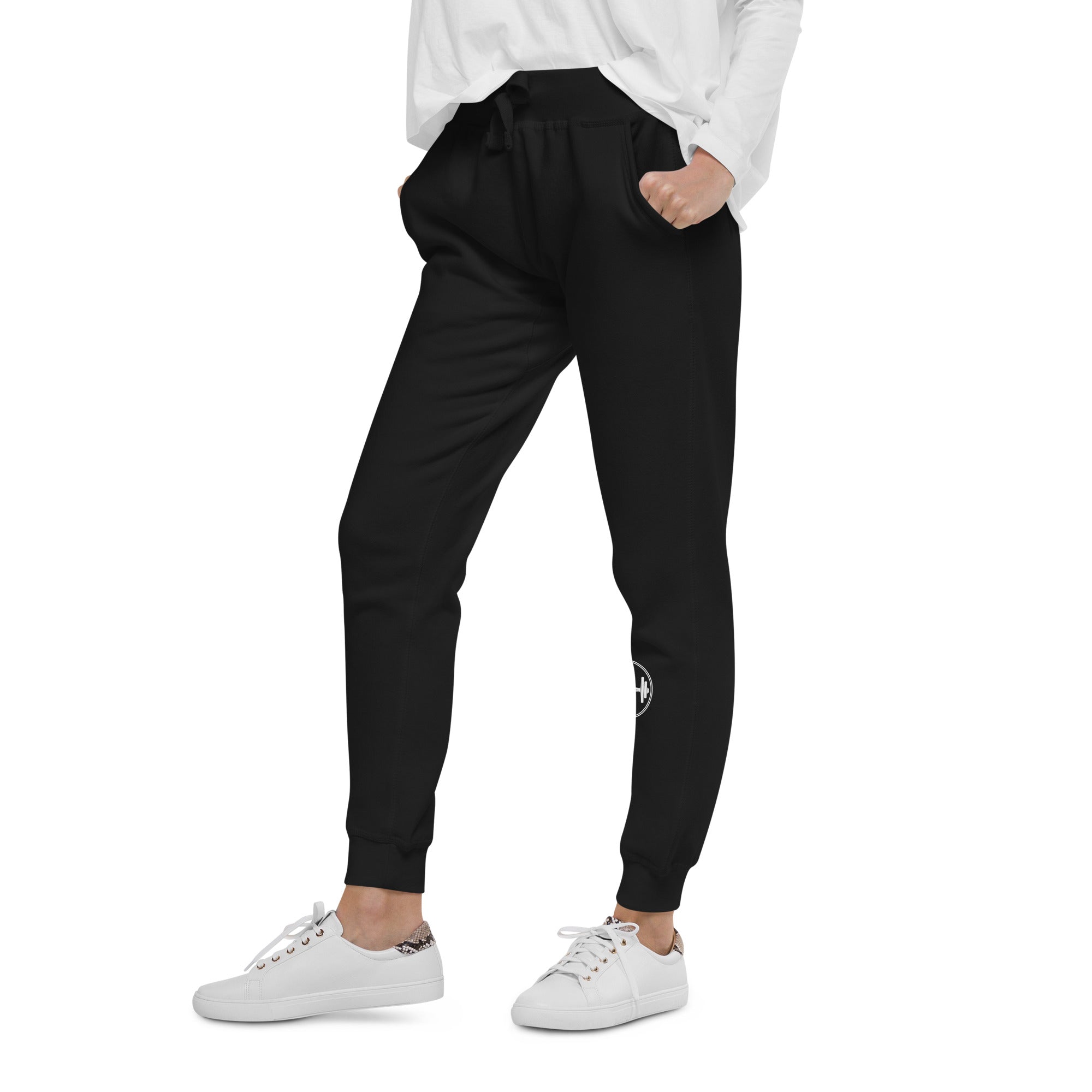 Person wearing black jogger pants and white sneakers on a white background